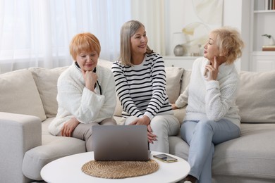 Friendship. Senior women watching something on laptop at home