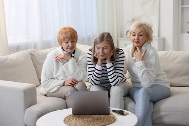 Friendship. Senior women watching something on laptop at home