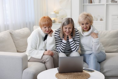 Friendship. Senior women watching something on laptop at home