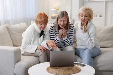 Friendship. Senior women watching something on laptop at home