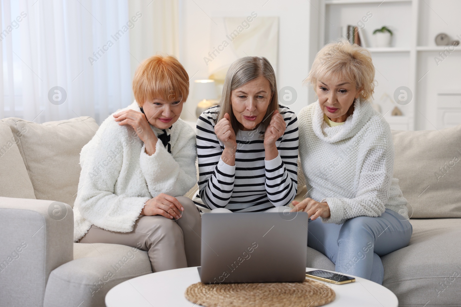 Photo of Friendship. Senior women watching something on laptop at home