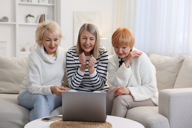 Friendship. Senior women watching something on laptop at home