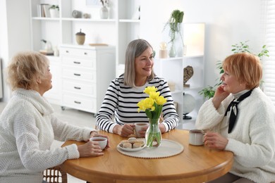 Photo of Friendship. Senior women enjoying hot drinks at table indoors