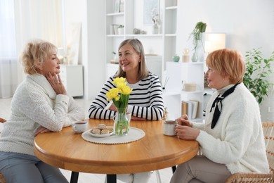 Photo of Friendship. Senior women enjoying hot drinks at table indoors