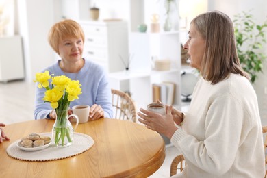 Photo of Friendship. Senior women enjoying hot drinks at table indoors