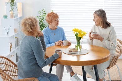 Photo of Friendship. Senior women enjoying hot drinks at table indoors