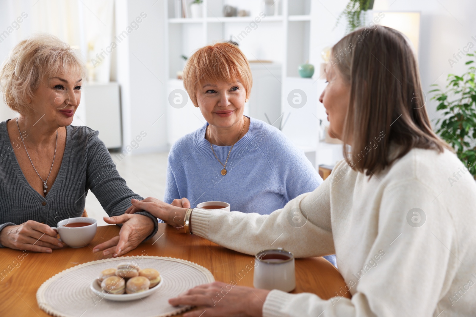 Photo of Friendship. Senior women enjoying hot drinks at table indoors