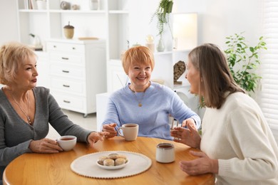 Photo of Friendship. Senior women enjoying hot drinks at table indoors