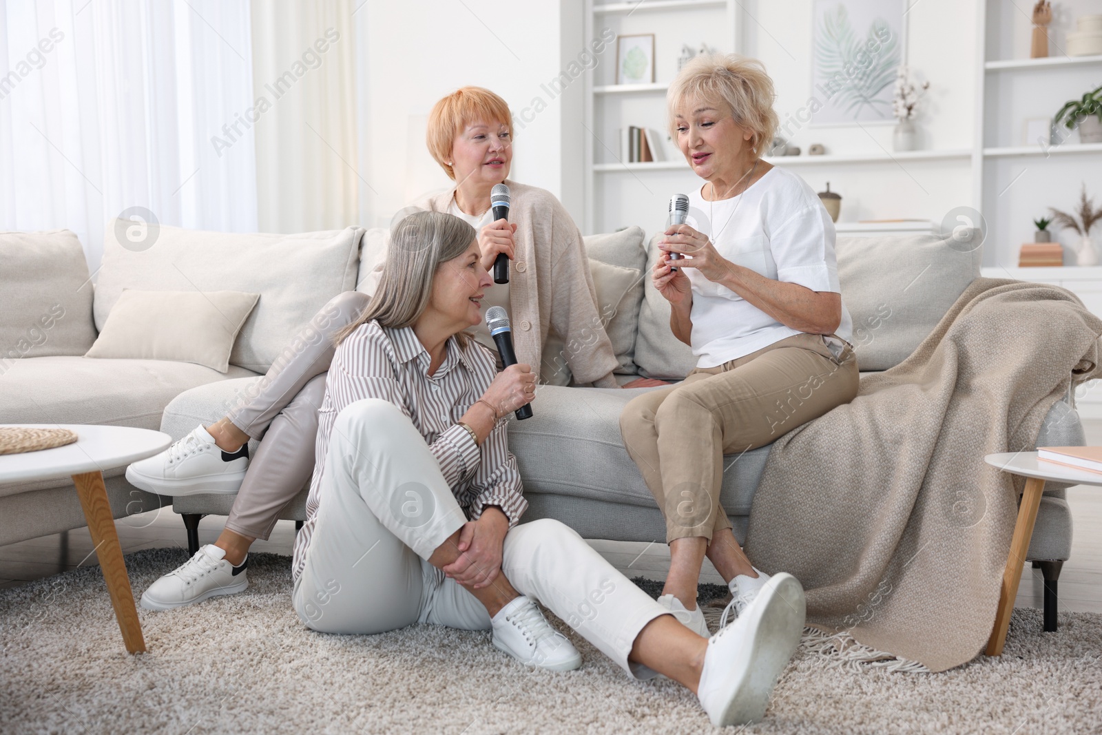 Photo of Senior woman singing karaoke with friends at home