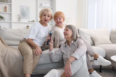 Senior woman singing karaoke with friends at home