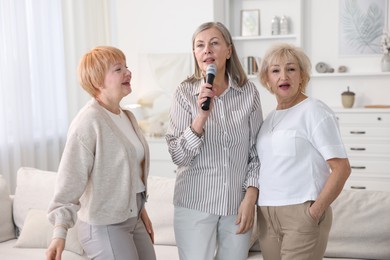 Senior woman singing karaoke with friends at home