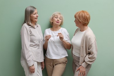 Photo of Friendship. Portrait of senior women on pale green background