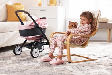 Photo of Cute little girl with her ginger cat sitting in armchair at home