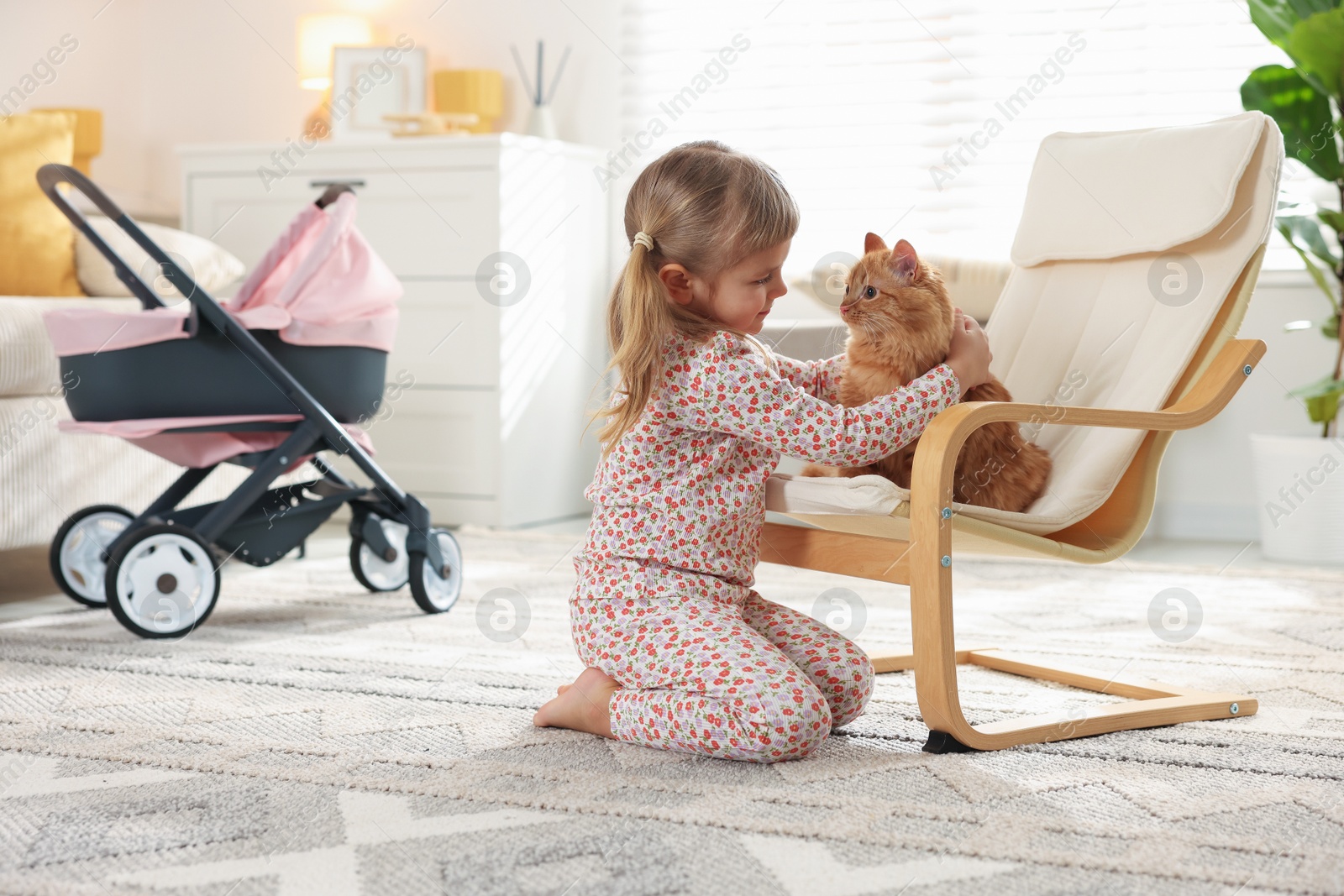 Photo of Cute little girl with her ginger cat at home