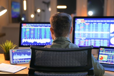 Photo of Financial trading specialist working in office at night, back view