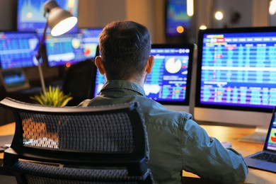 Financial trading specialist working in office at night, back view