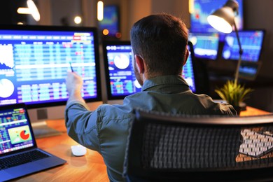 Financial trading specialist working in office at night, back view