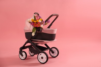 Photo of Stylish doll stroller and tulips on pink background, space for text. Kid's toy