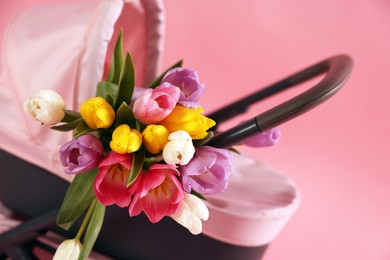 Photo of Stylish doll stroller and tulips on pink background, closeup. Kid's toy