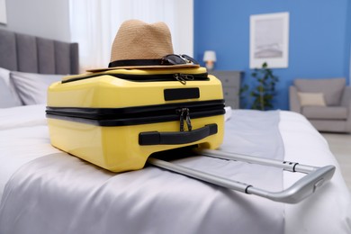 Suitcase with hat and sunglasses on bed in hotel room