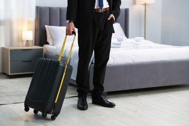 Businessman with suitcase in hotel room, closeup