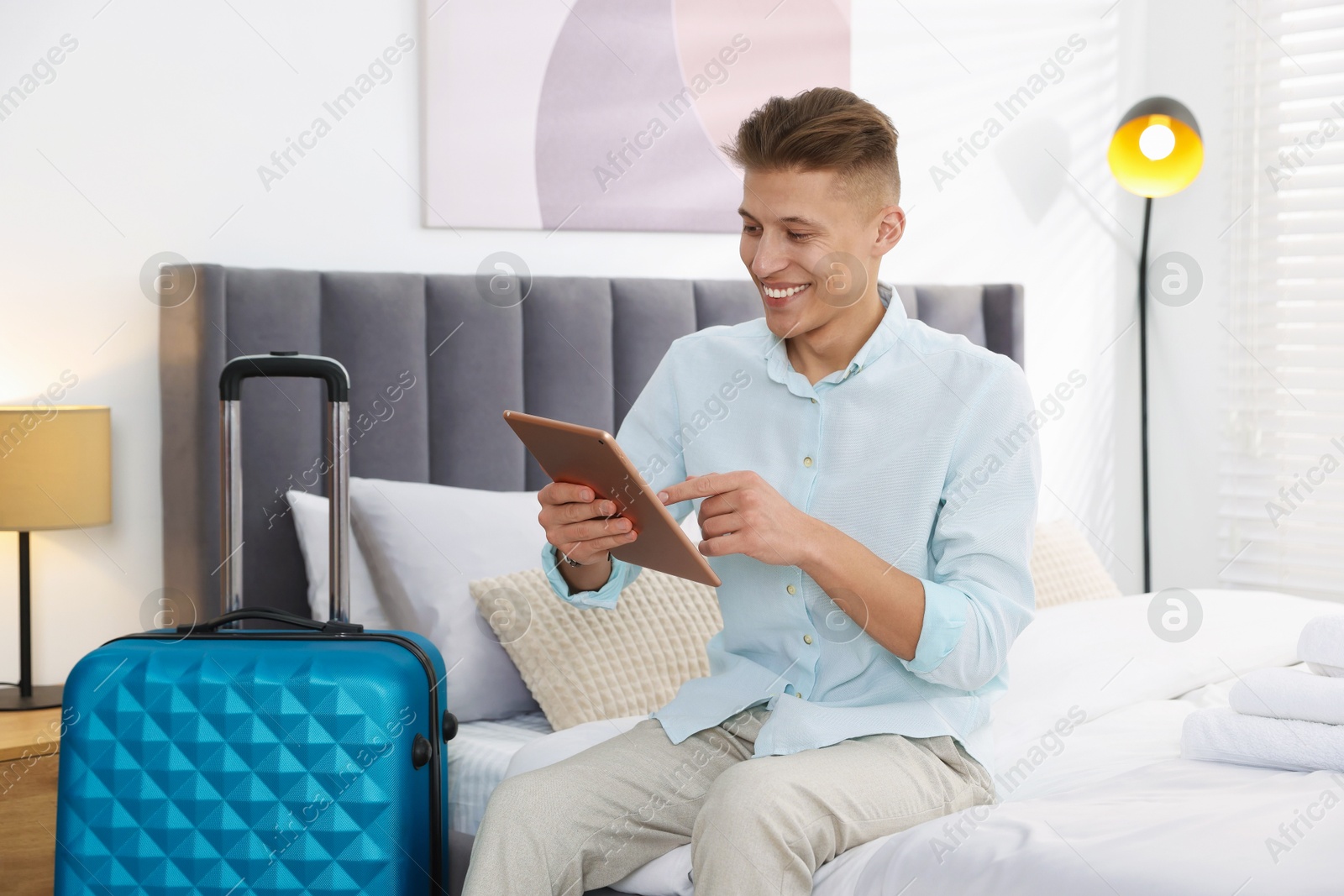 Photo of Man with tablet on bed in his hotel room