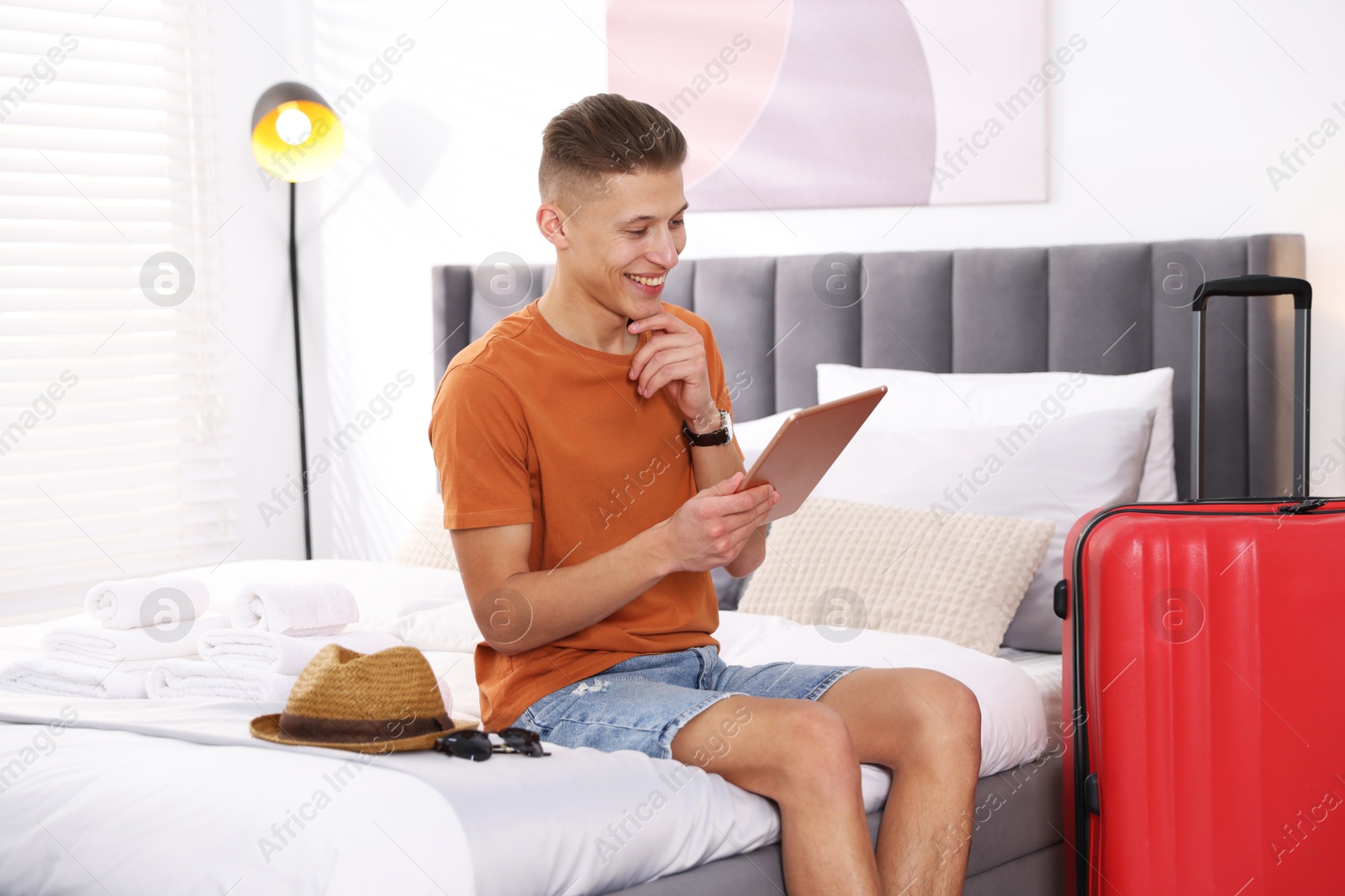 Photo of Man with tablet on bed in his hotel room