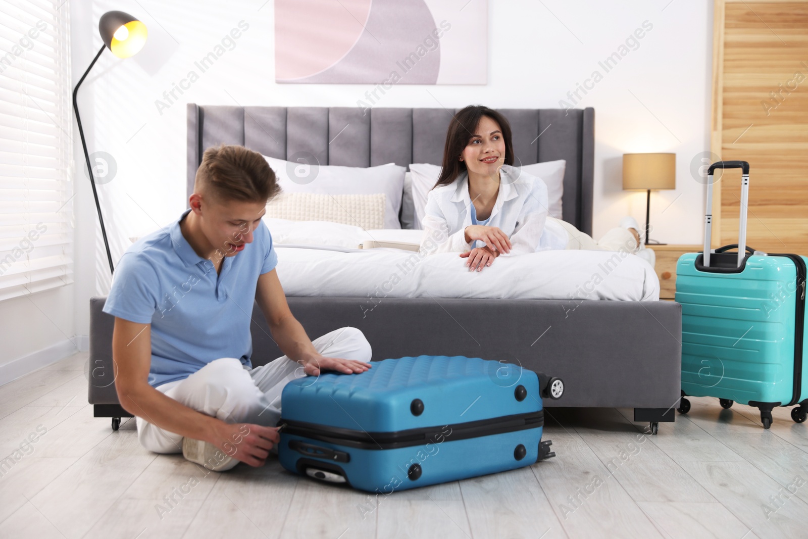 Photo of Happy couple unpacking their suitcases in hotel room