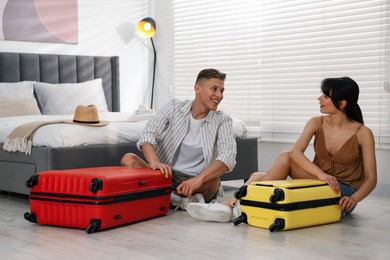 Happy couple unpacking their suitcases in hotel room