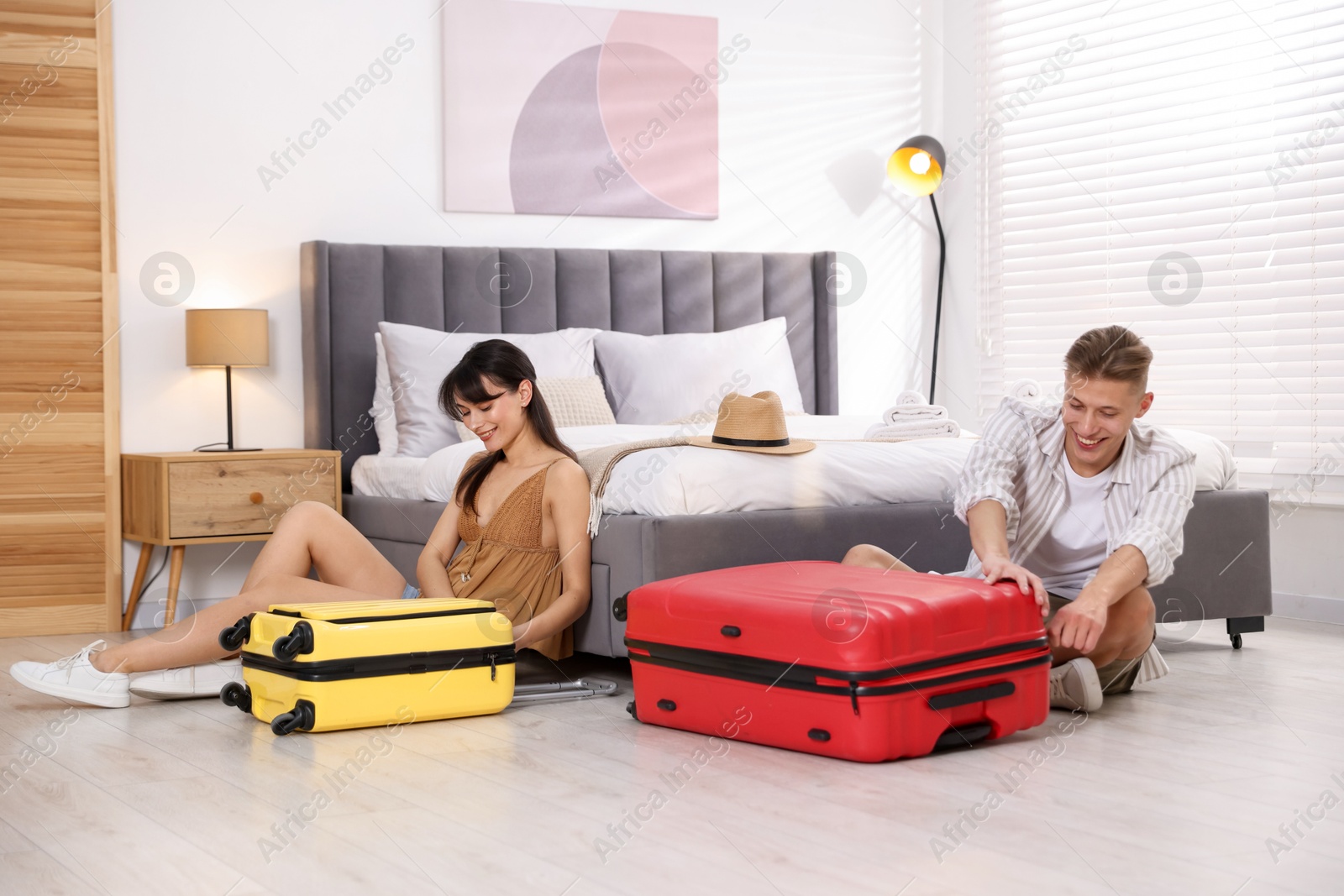 Photo of Happy couple unpacking their suitcases in hotel room