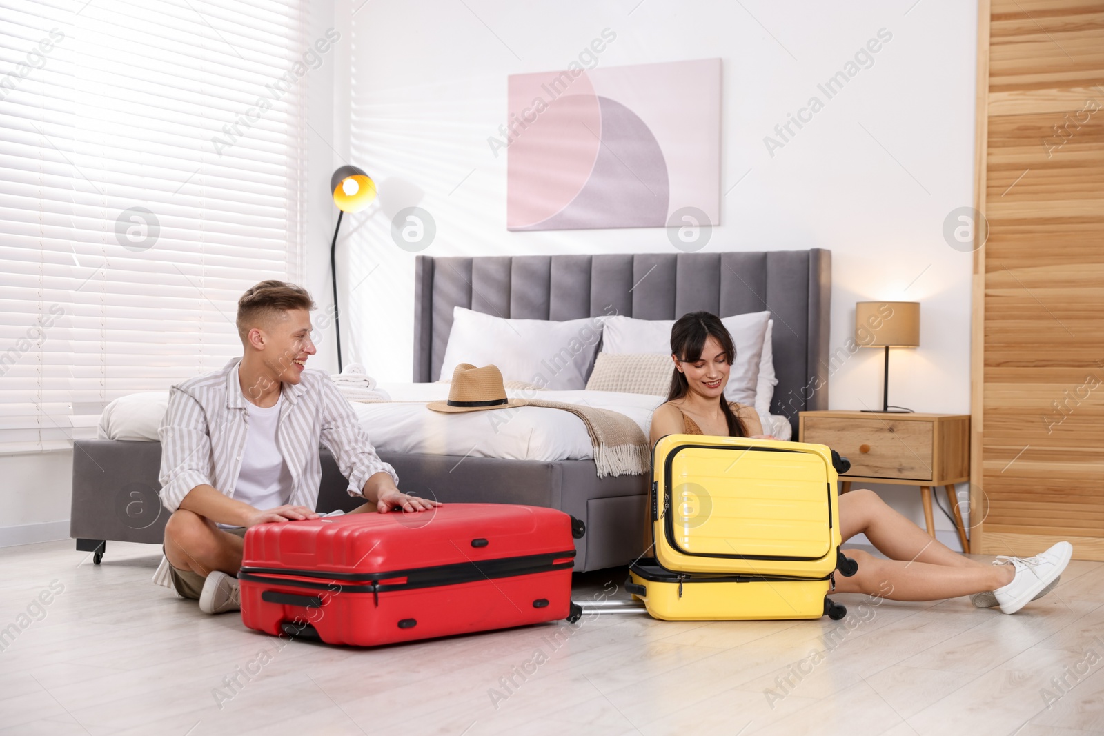 Photo of Happy couple unpacking their suitcases in hotel room