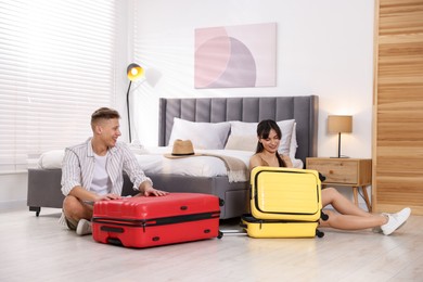 Photo of Happy couple unpacking their suitcases in hotel room