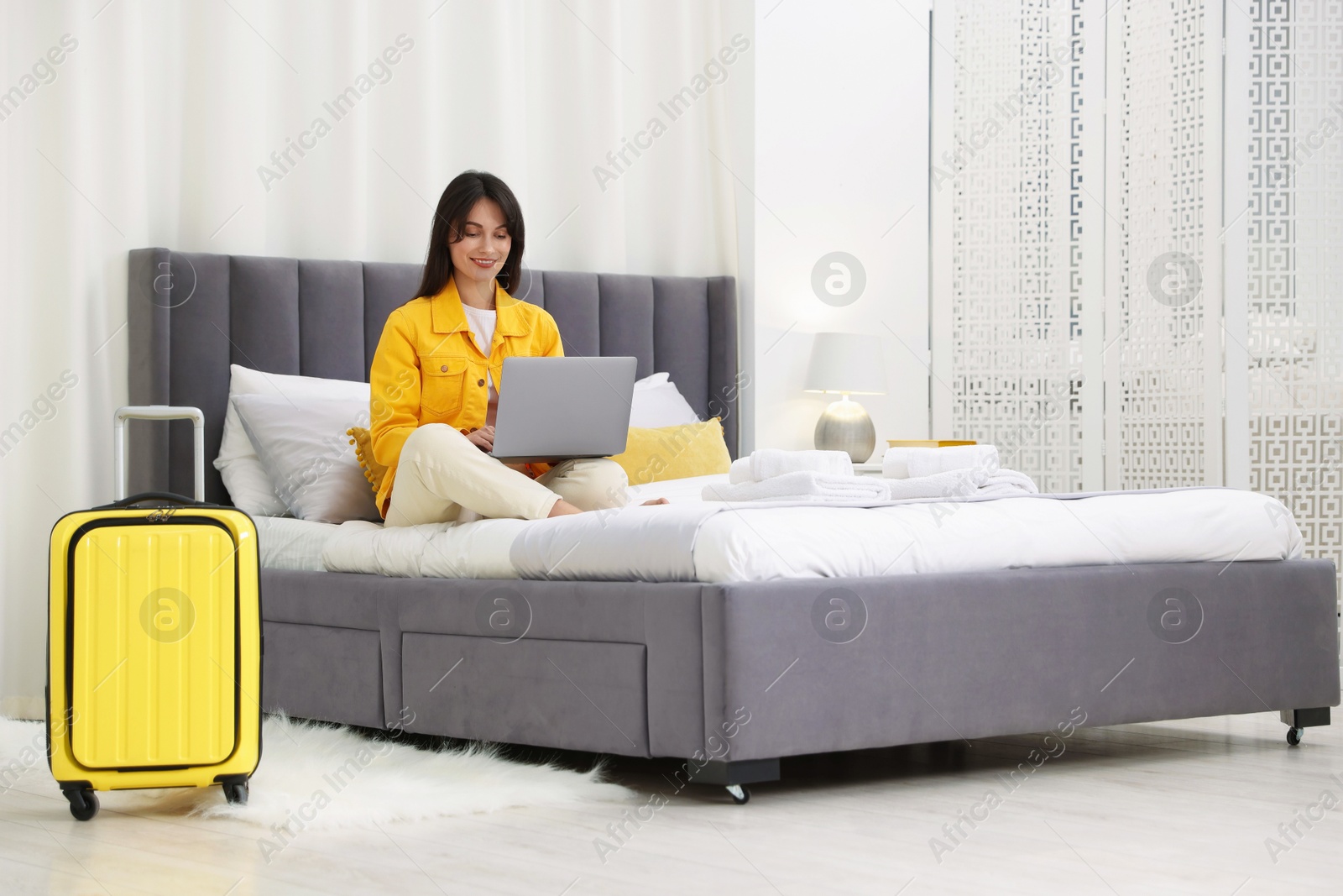 Photo of Woman with laptop on bed in her hotel room