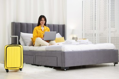 Woman with laptop on bed in her hotel room