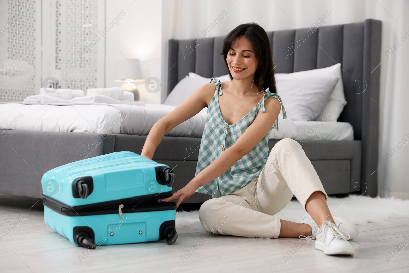 Photo of Woman unpacking her suitcase in hotel room