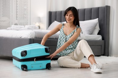 Woman unpacking her suitcase in hotel room