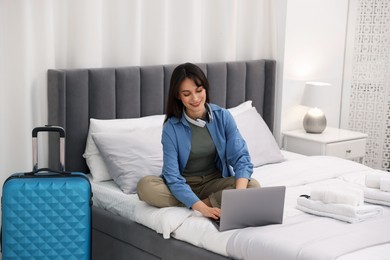 Photo of Woman with laptop on bed in her hotel room