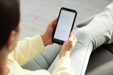 Photo of Menstruation. Woman using period calendar application on smartphone indoors, closeup