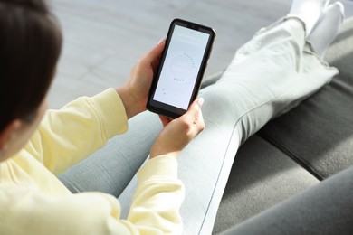 Photo of Menstruation. Woman using period calendar application on smartphone indoors, closeup