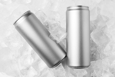 Photo of Refreshing drinks in cans on ice cubes, top view