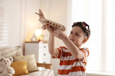 Photo of Happy little boy playing with toy plane at home