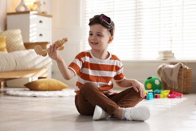 Photo of Happy little boy playing with toy plane at home