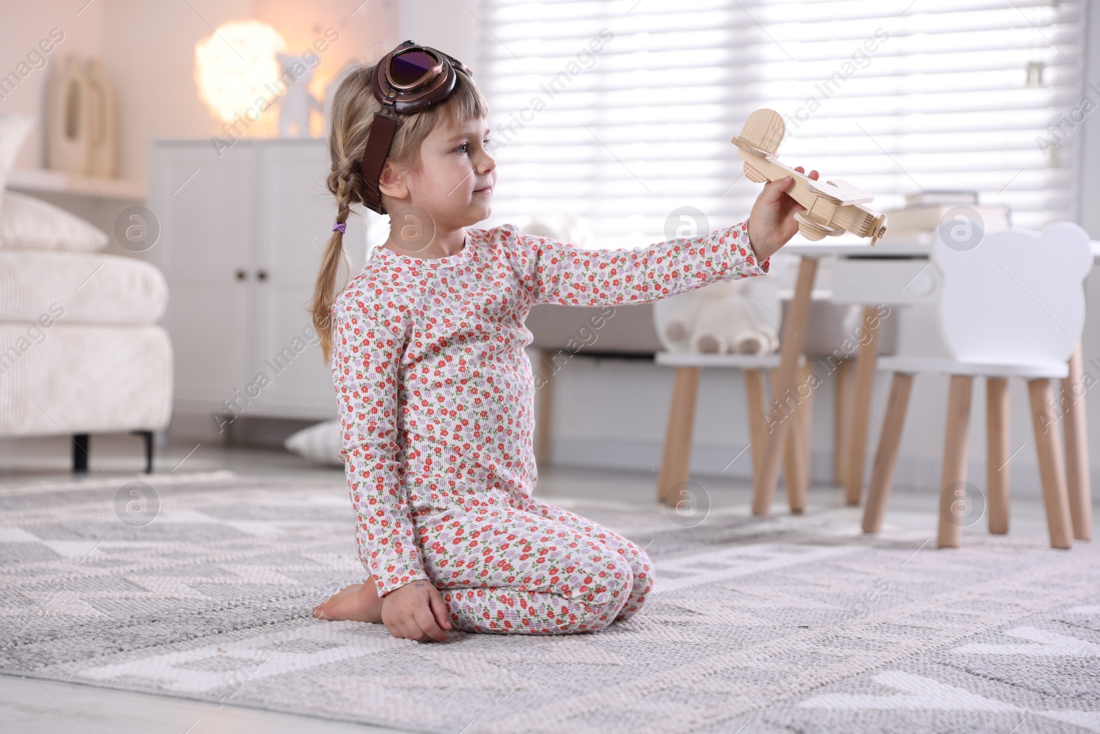 Photo of Cute little girl playing with toy plane at home