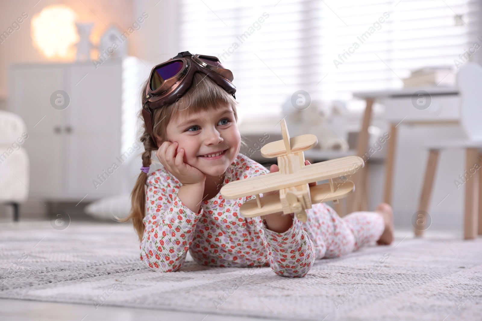 Photo of Cute little girl playing with toy plane at home