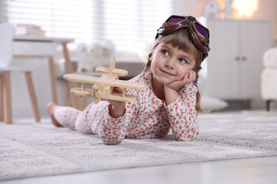 Photo of Cute little girl playing with toy plane at home