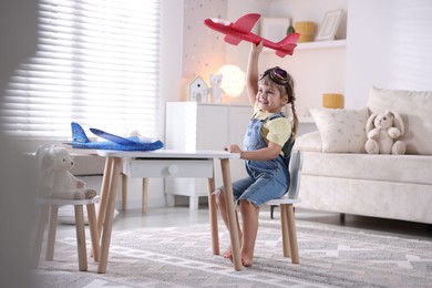 Cute little girl playing with toy plane at home