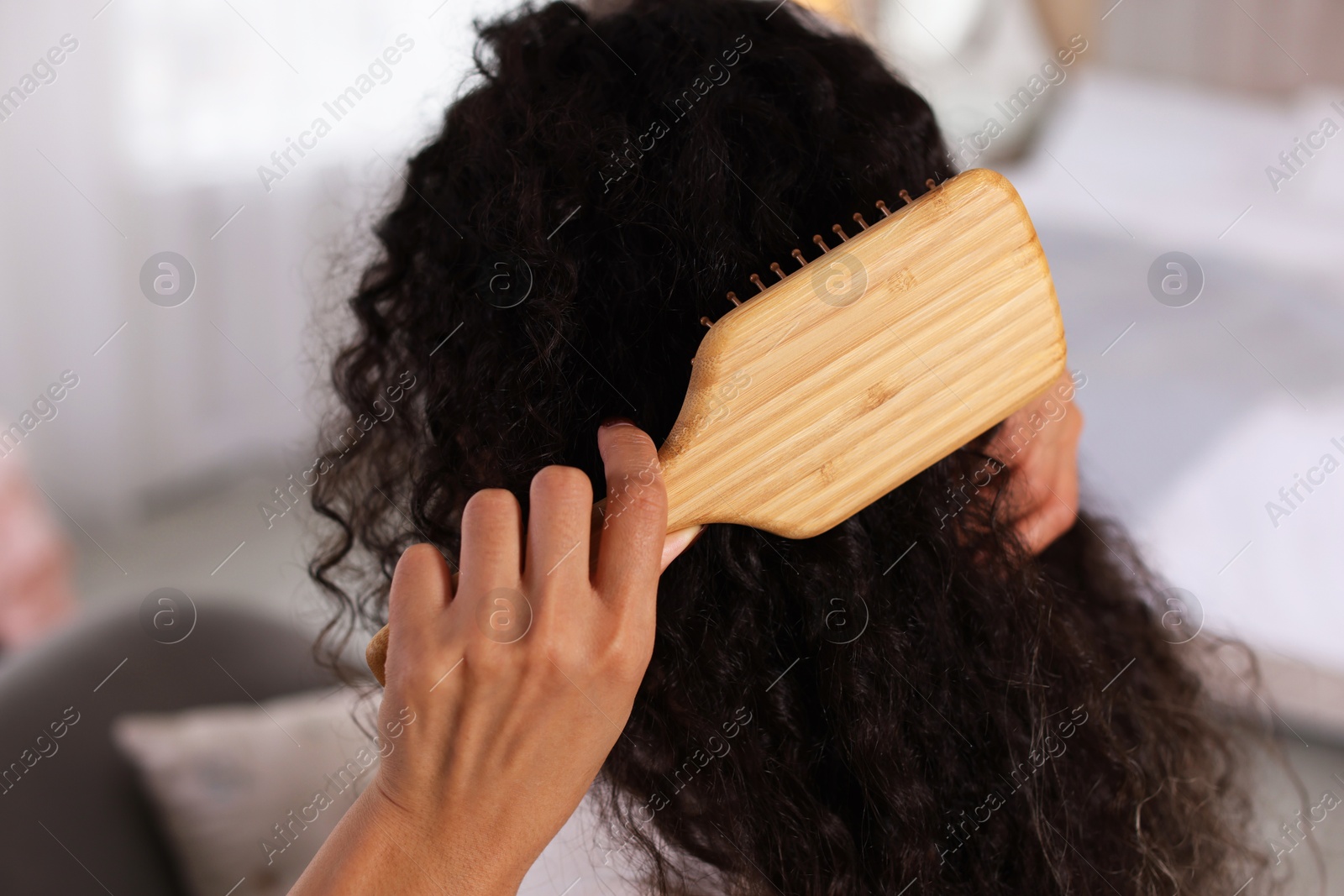 Photo of Woman brushing her curly hair at home