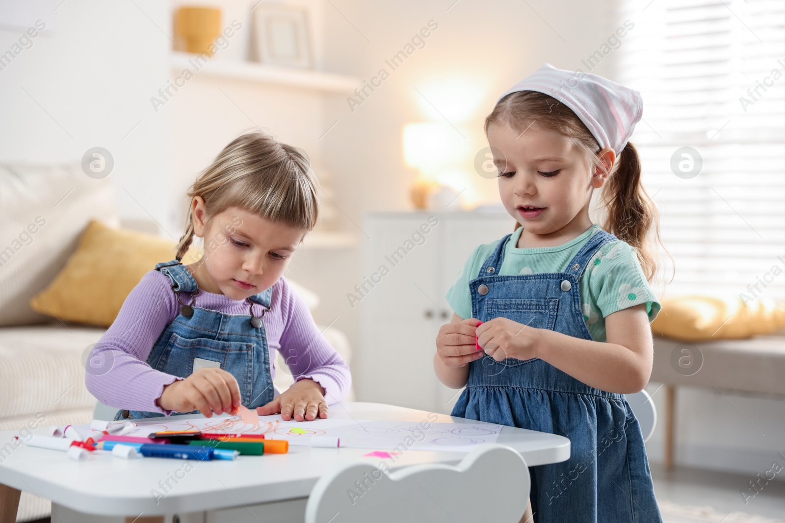 Photo of Cute little sisters drawing at white table in room