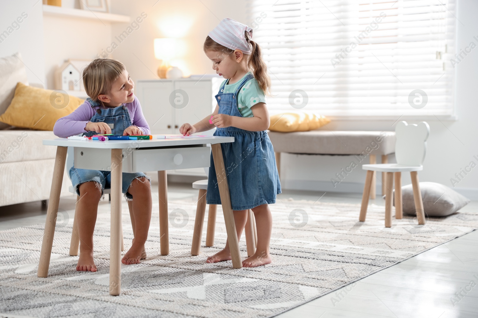 Photo of Cute little sisters drawing at white table in room