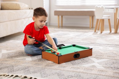 Photo of Cute little boy playing billiards at home